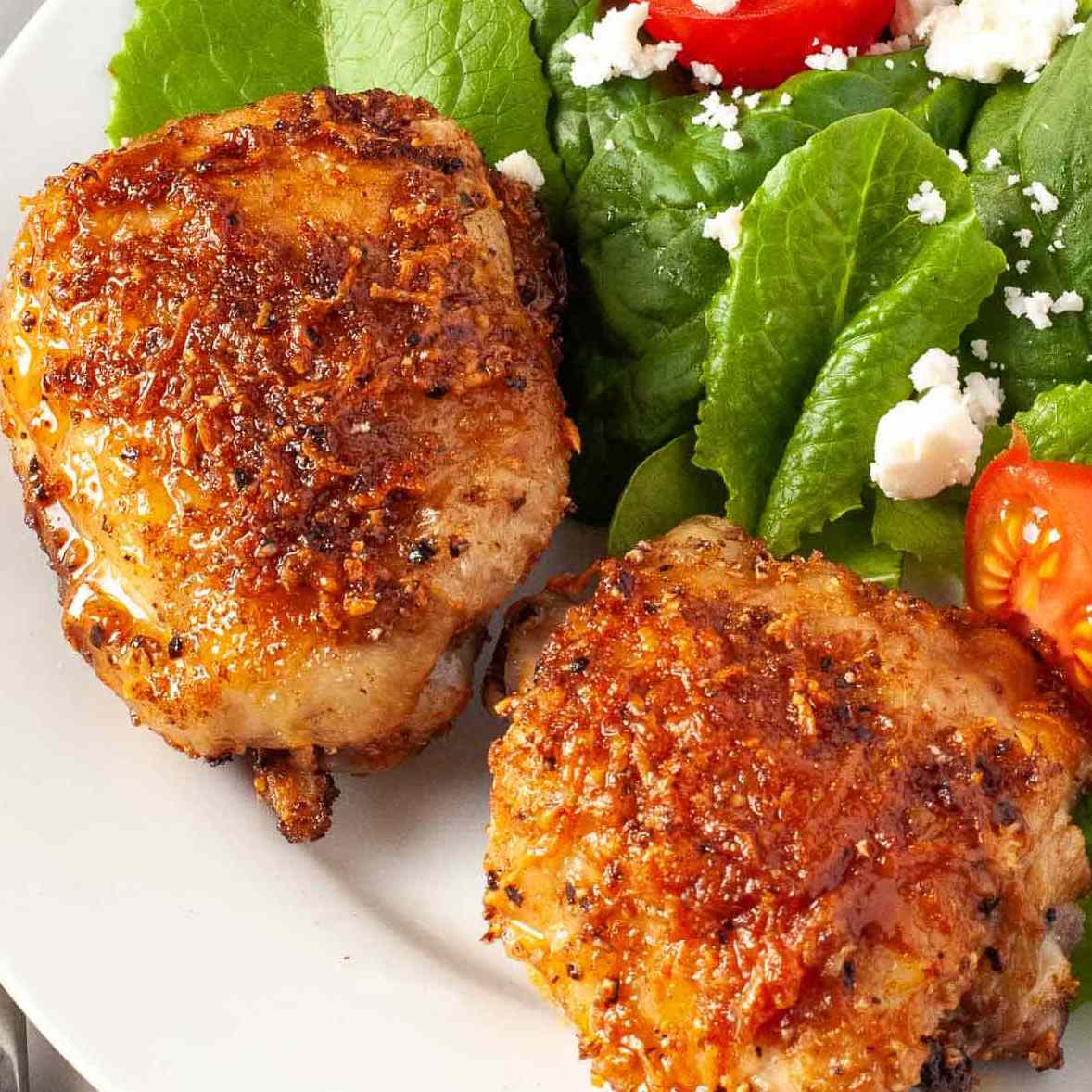 两份涂有帕尔马干酪的鸡胸肉，放在沙拉旁边的盘子里