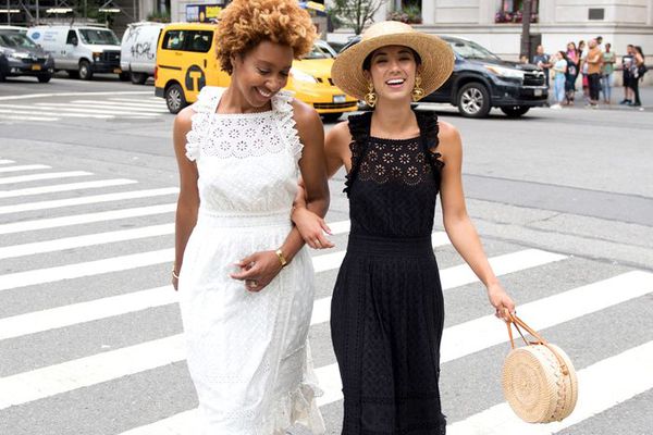 两个女人手挽手走在交叉人行道上