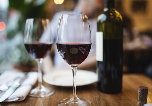 Two glasses of red wine and a bottle on a wooden table