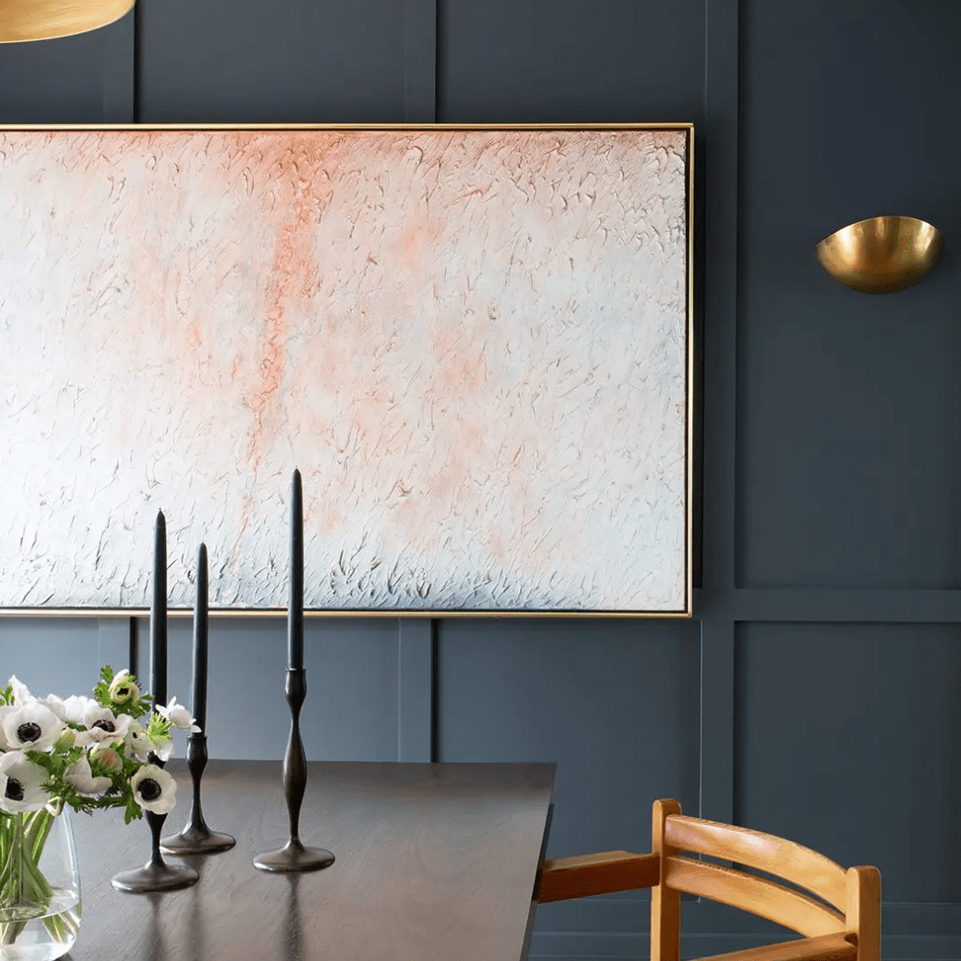 一间餐厅，靛蓝色的墙壁上有一幅浅粉色的画