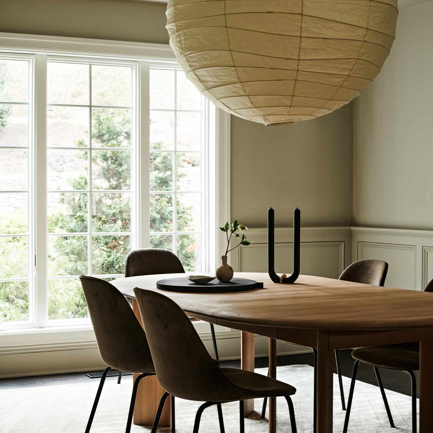 一张木制餐桌，上面有一根黑色的u形蜡烛，一个黑色的托盘和一小瓶花