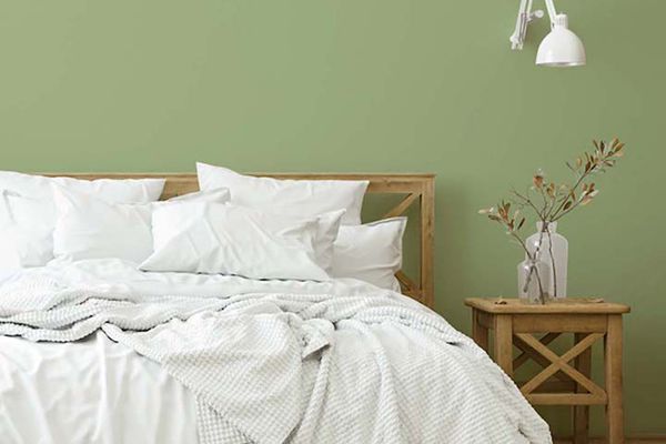 舒适的卧室，白色床上用品，墙上挂着鳄梨色拉酱。