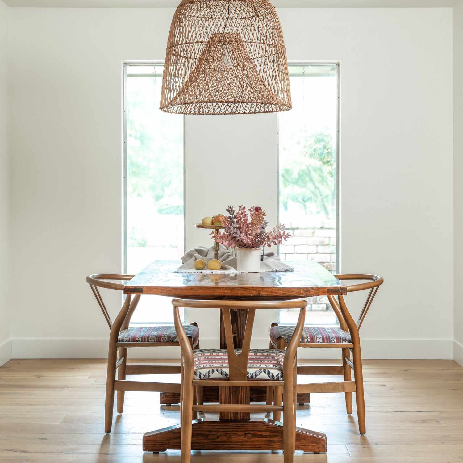 一张木制餐桌，上面放着一瓶鲜花和一个水果摊，这两件东西都被放在一条捆成一团的毛巾上