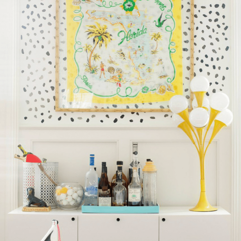 A bar cart with black speckled wallpaper over it