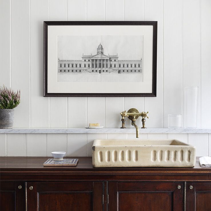 一个有白色墙壁，桃花心木家具和古董米色水槽的房间