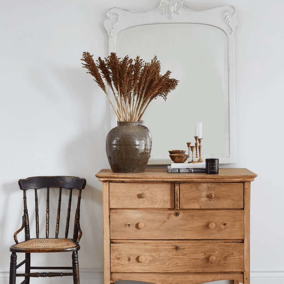 一套质朴的木橱柜，顶部是一面漆成白色的古董镜子