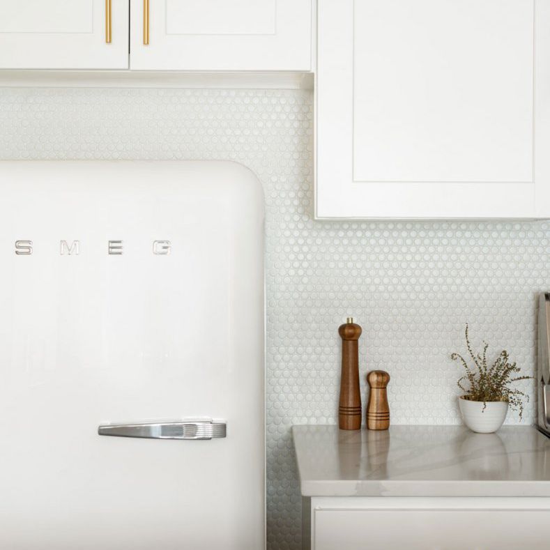 一个全白色的厨房，墙壁衬有一分钱瓷砖