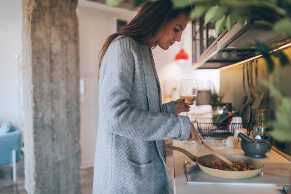 年轻女子一边做饭一边喝酒