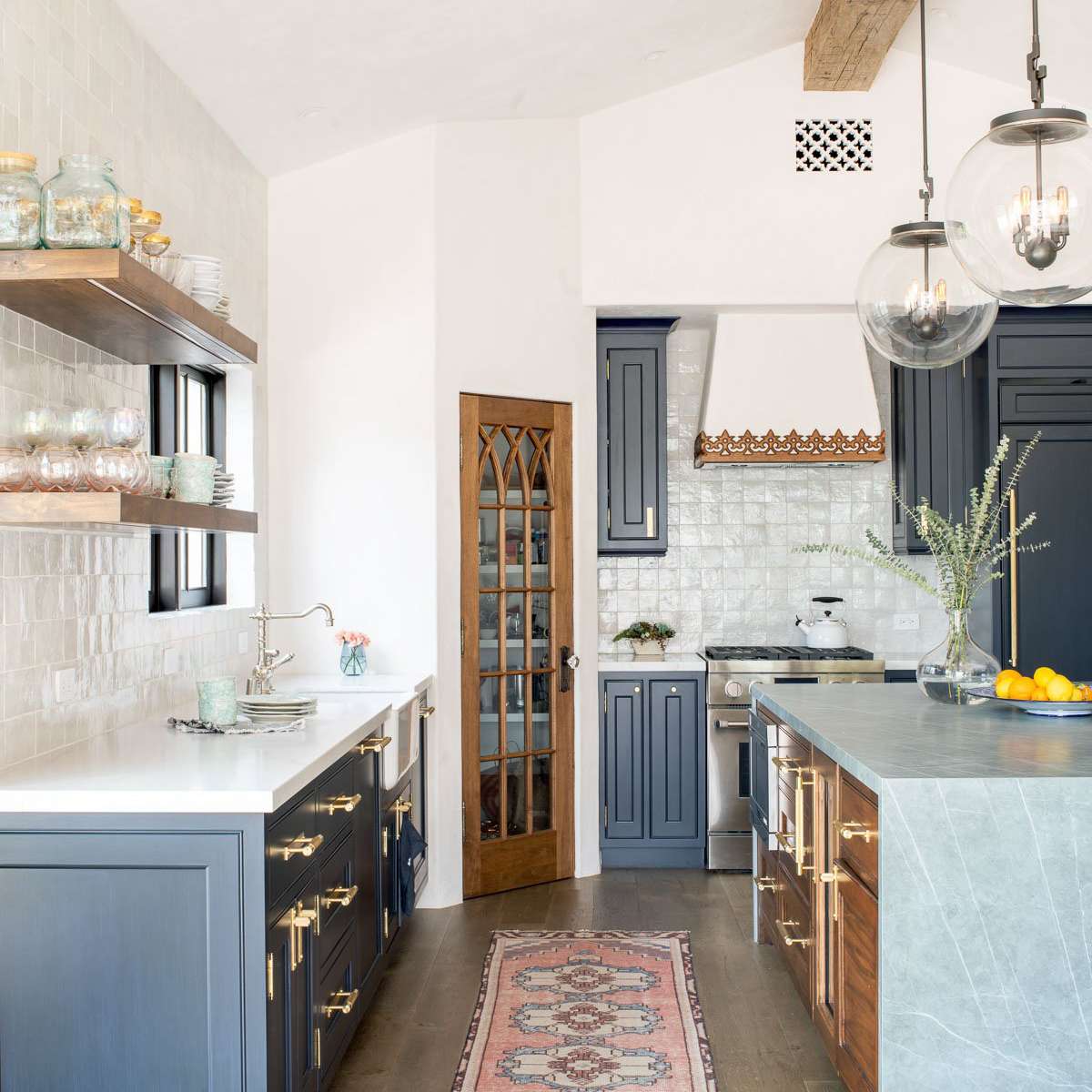 厨房里有海军蓝的橱柜、大理石台面和粉红色的地毯