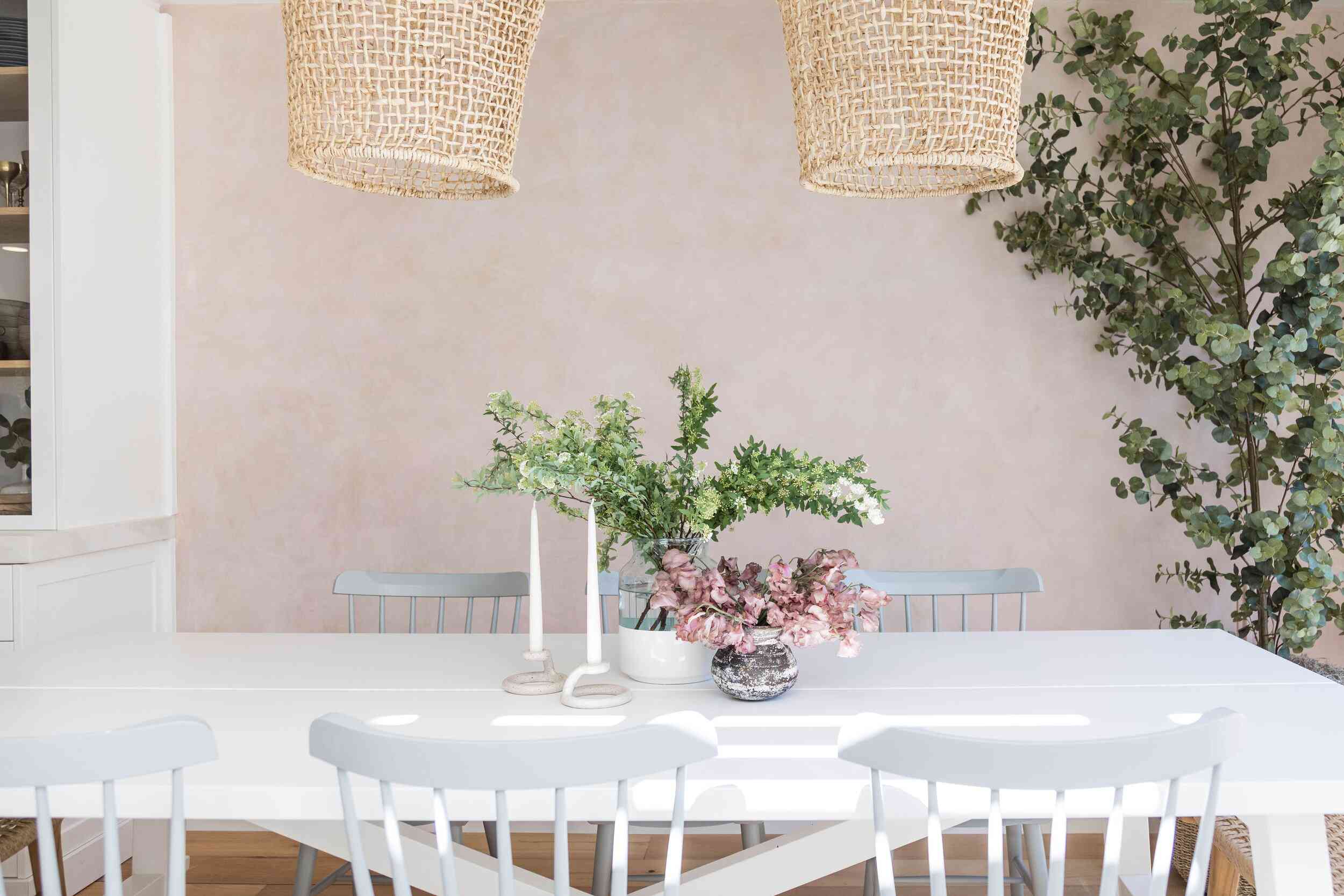 一张白色的餐桌，上面装饰着两支白色的蜡烛和两个装满鲜花的花瓶