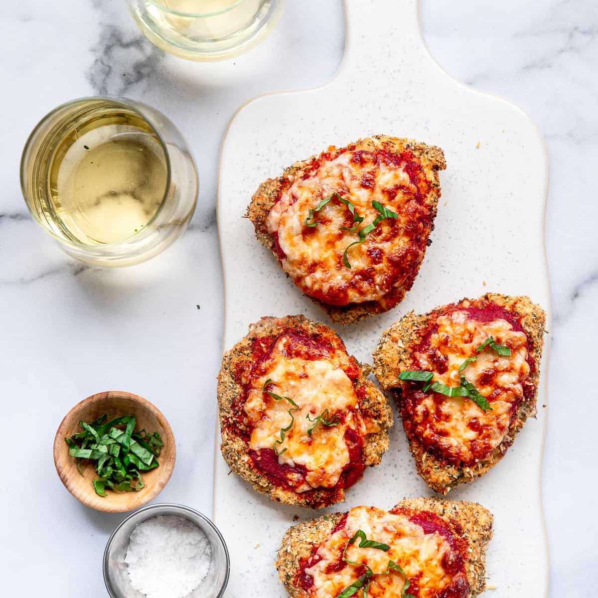 四份帕尔马干酪鸡肉装在大浅盘上