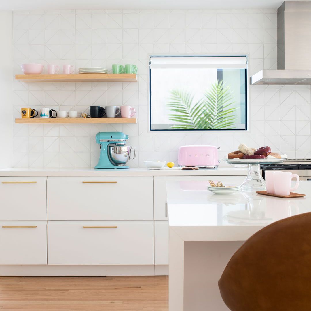 一个全白色厨房，带有三角形瓷砖衬里的背板