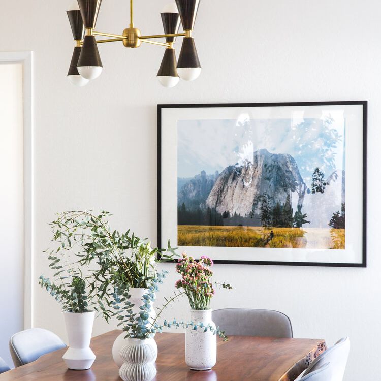 餐厅的桌子上装饰着四个白色的花瓶，所有花瓶上都插满了树枝和鲜花