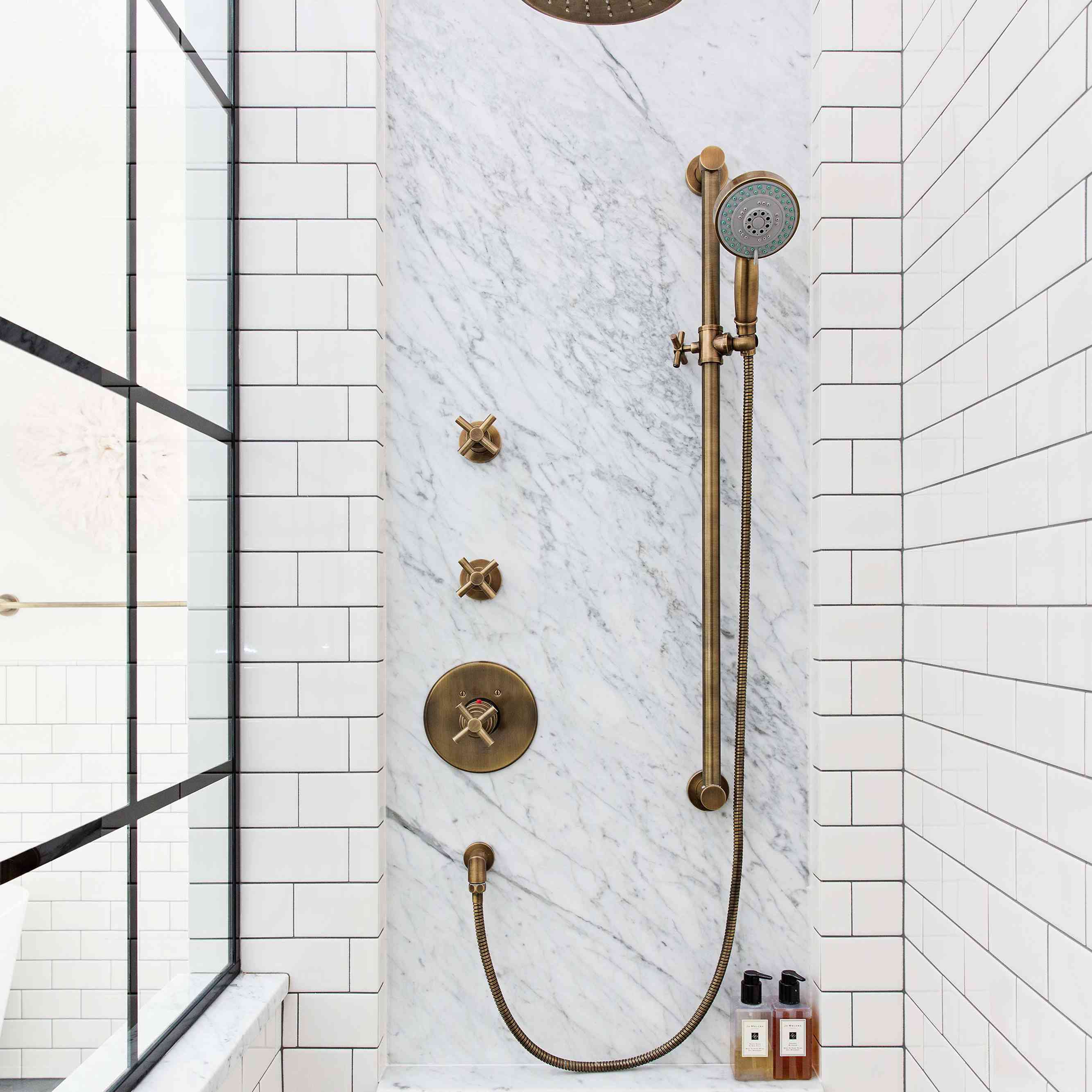 A white tile-lined shower with pops of textured marble