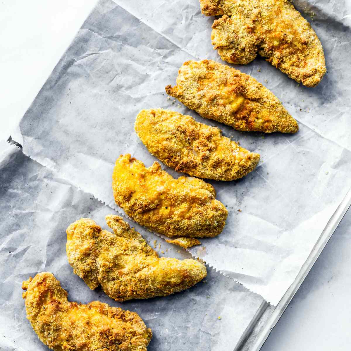 一排涂了面包屑的鸡柳放在羊皮纸上