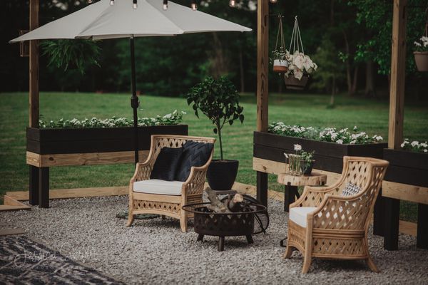 后院有两把扶手椅和一把伞，周围是花盆”class=