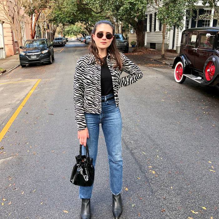 棕色头发的女孩穿着高层牛仔裤，条纹印刷夹克，墨镜和黑色皮靴