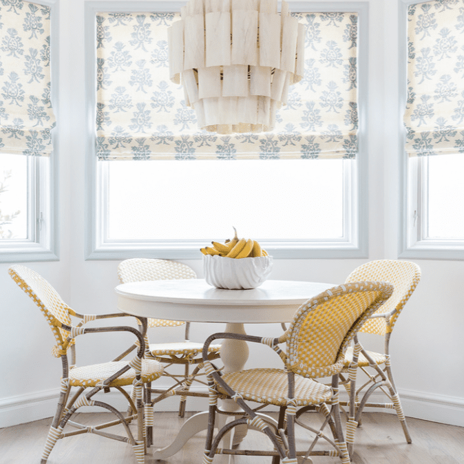 这是一张厨房桌子，上面装饰着黄色的编织椅和淡蓝色的罗马图案