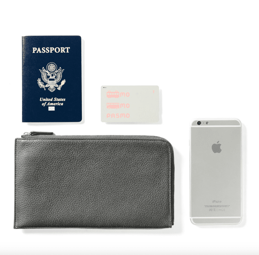 一个灰色的旅行钱包，旁边放着iPhone手机、护照和交通车票。