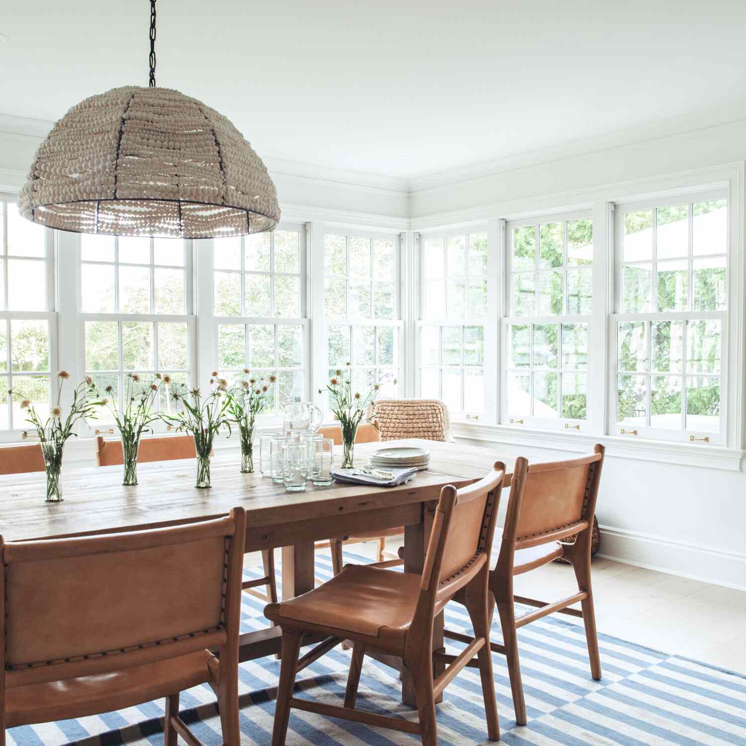 餐厅的桌子上装饰着五个小玻璃花瓶，所有的花瓶都装满了野花