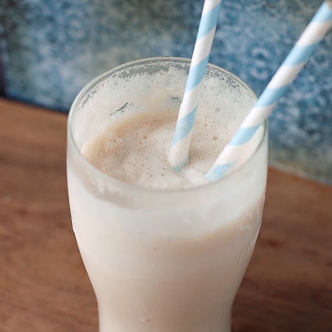一杯有两根吸管的高脚杯里的酒奶昔。