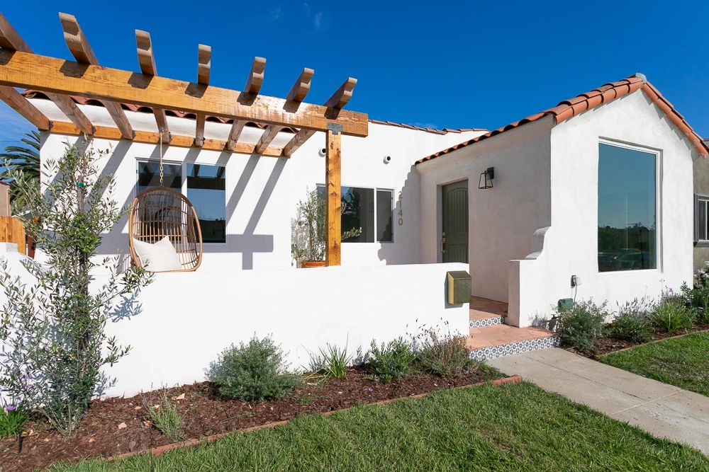 有凉棚和垂悬的椅子的白色外部房子。