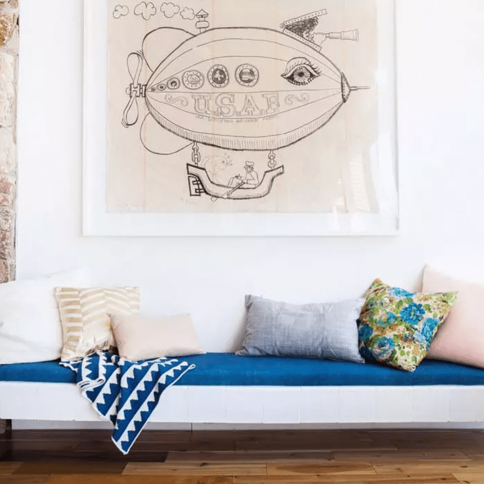 白色的墙壁上摆放着不同尺寸和图案的靠枕