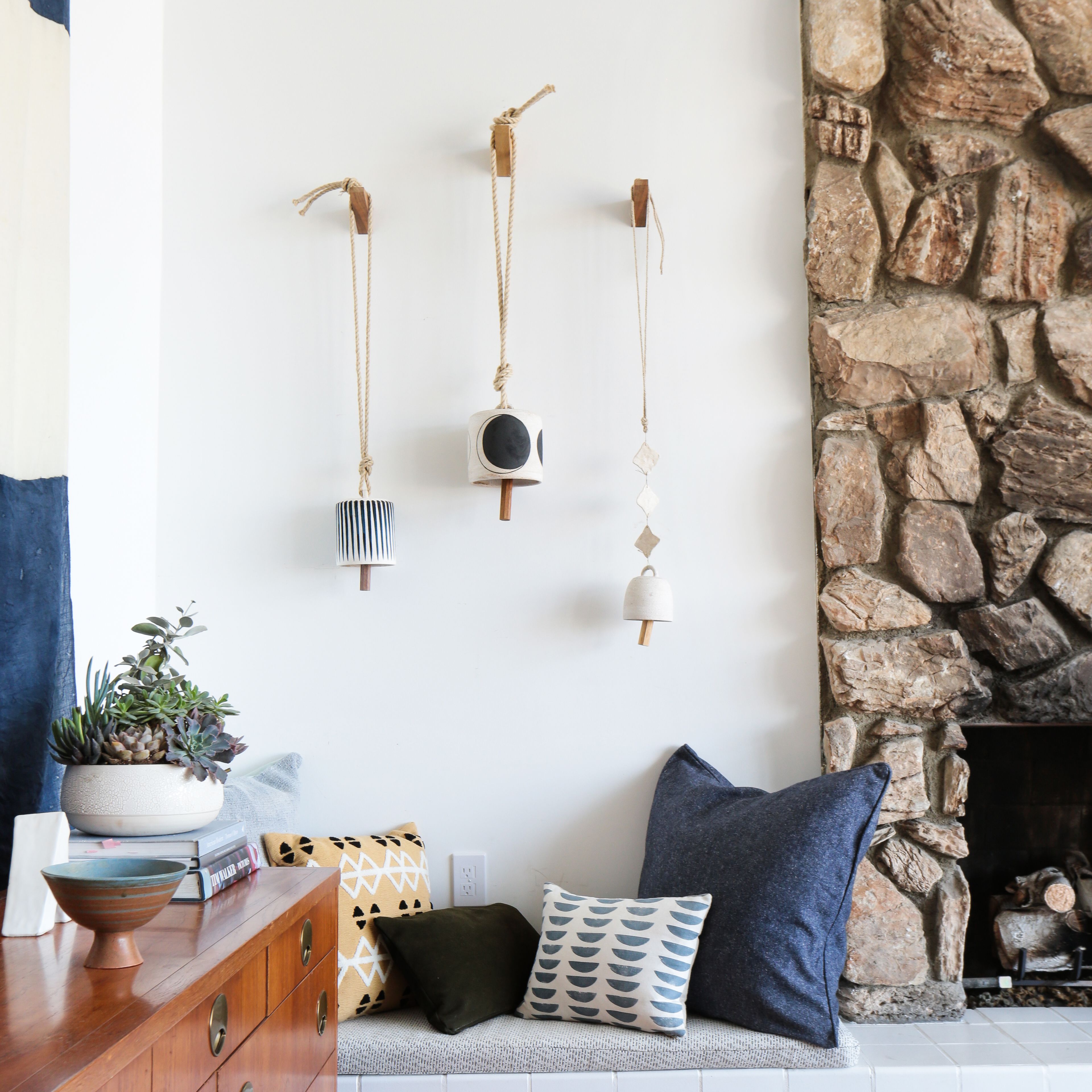 壁炉旁边有枕头的起居室长凳“class=