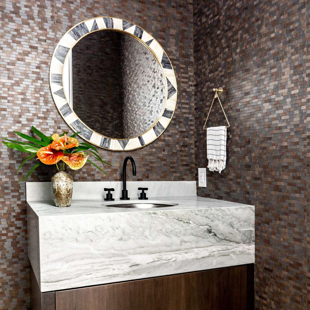 盥洗室里有金属瓷砖砌成的墙壁，一面醒目的圆形镜子，还有一个大理石洗手池