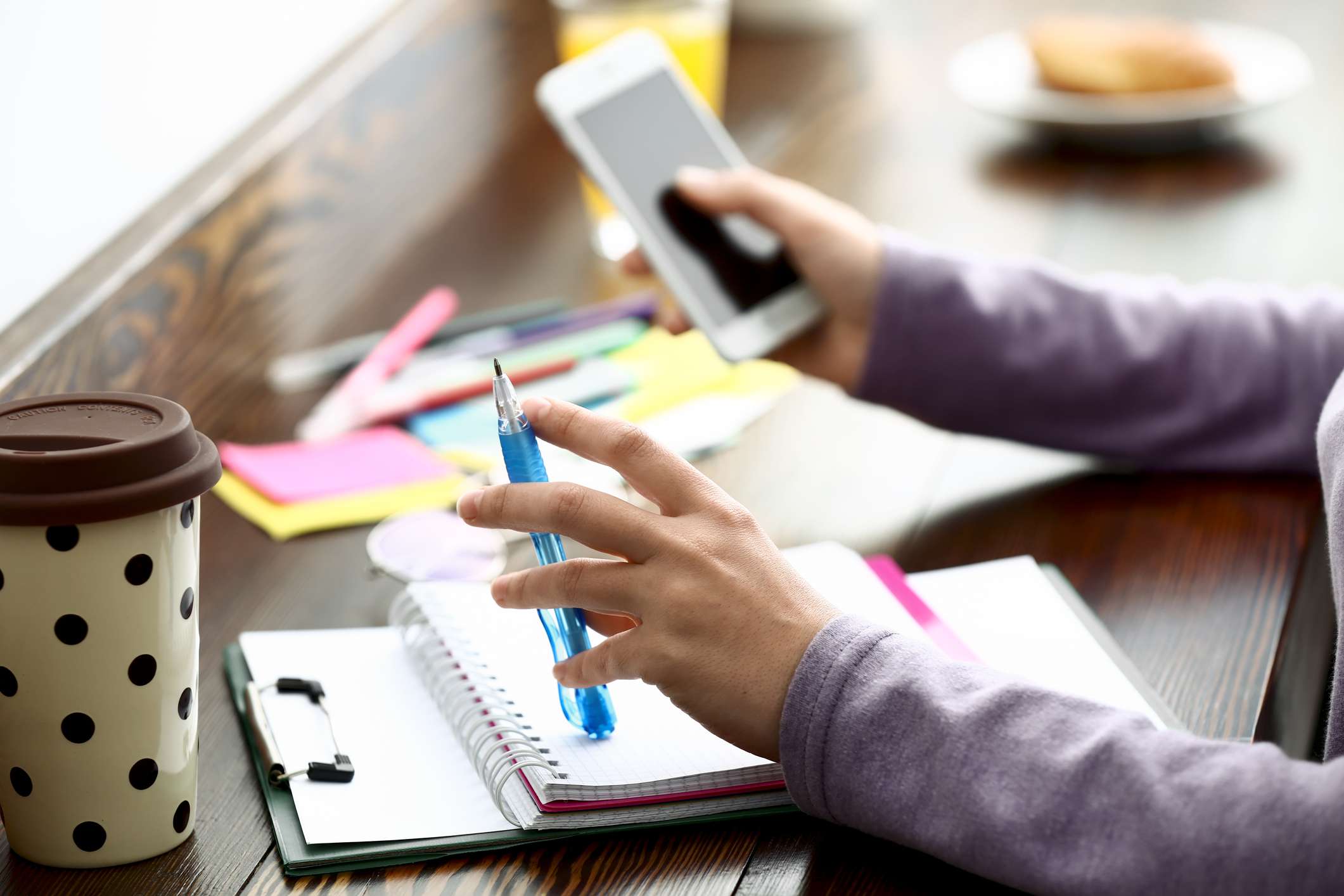 人持有铅笔在智能手机在期刊和外观。