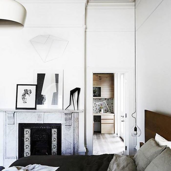 卧室有白色的墙壁，床上有灰色和黑色的被褥