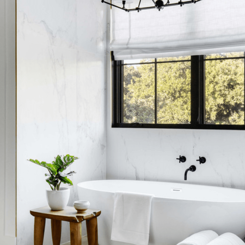 浴室装满了配件，如木浴缸凳子和一个装满毛巾的编织篮