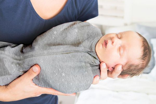 抱着襁褓中熟睡的婴儿的妇女