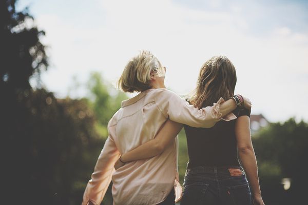 在户外行走的胳膊的妇女背面图