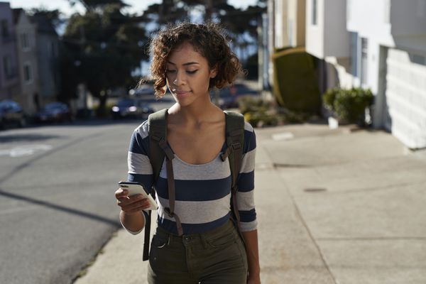 Young woman walks up steep hill, texting