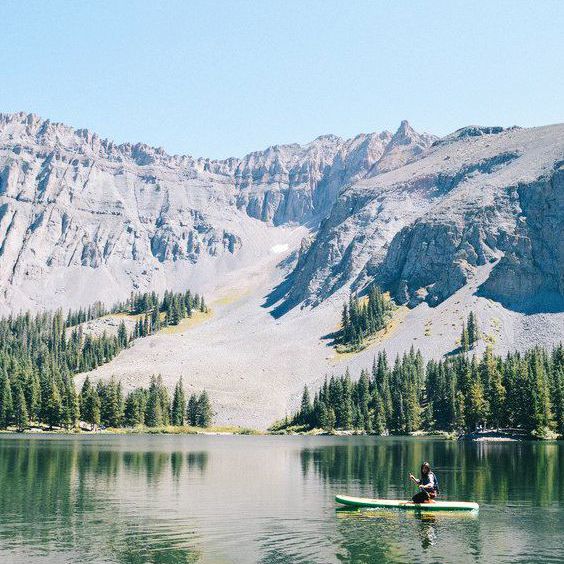 个人在桨板上的水体与山脉为背景