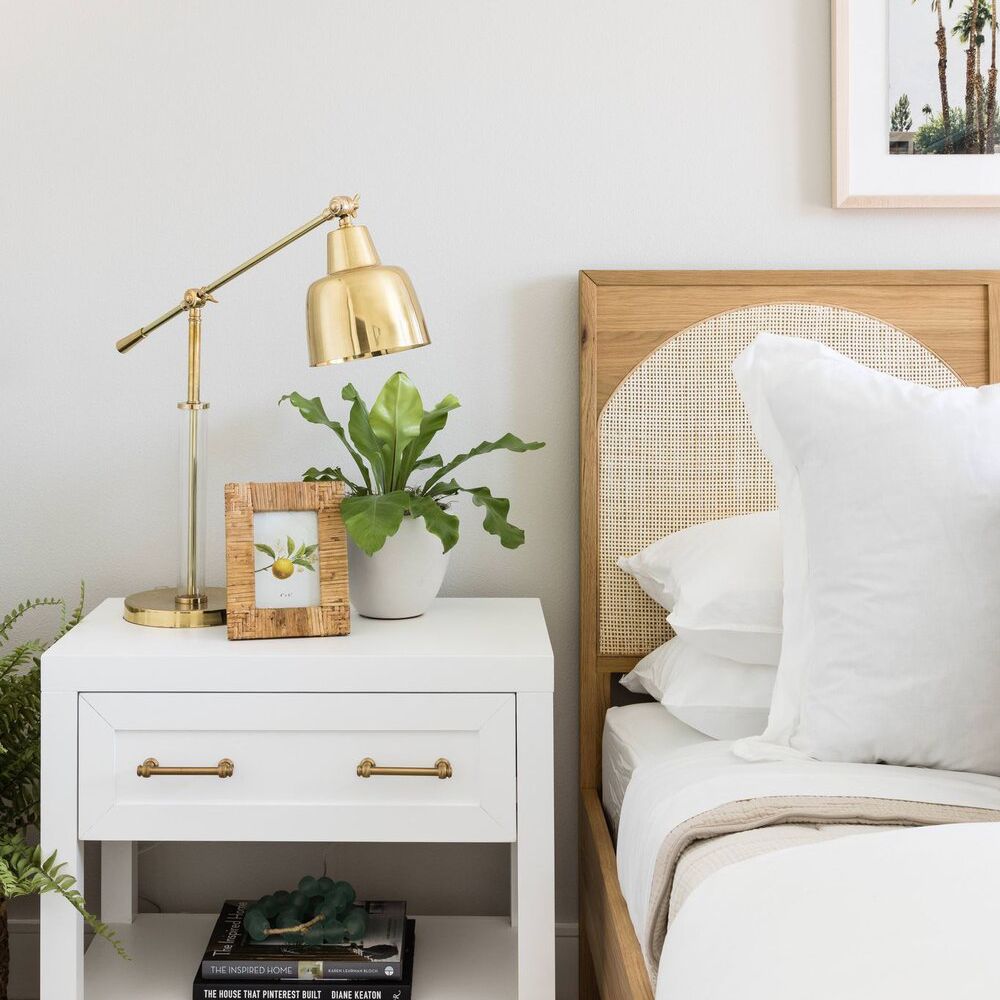 一间极简主义风格的卧室，配有一盏光滑的金色台灯