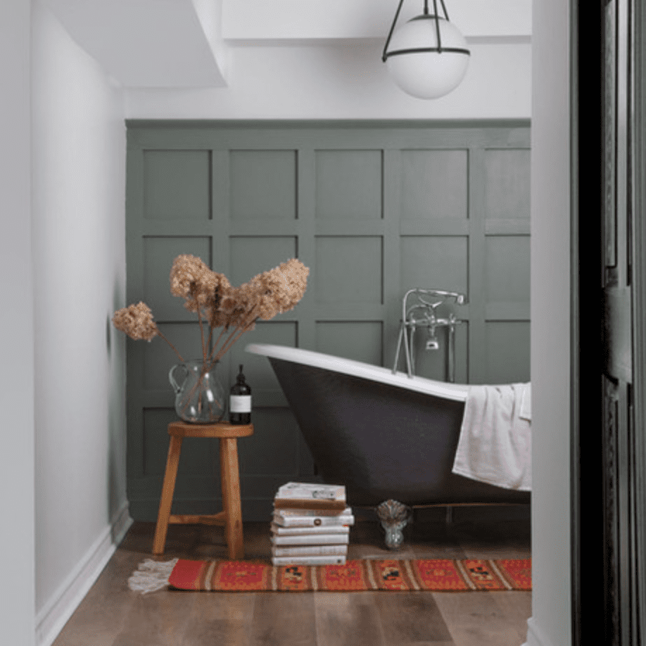 用灰绿色的墙壁，硬木地板，一个小型木凳子甲浴室和红色印刷地毯