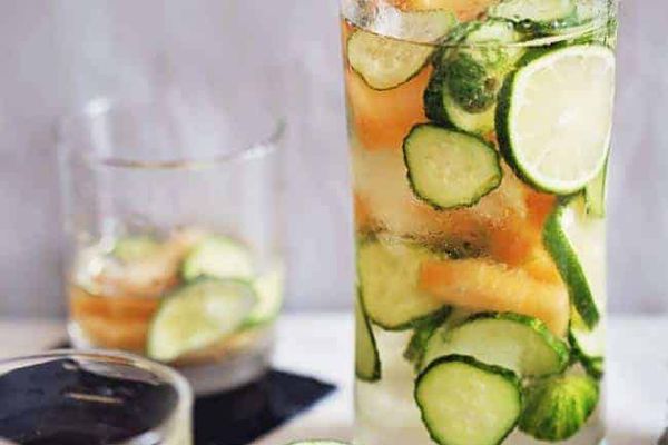 在一个投手的白色桑格里亚装满了黄瓜，石灰和瓜。