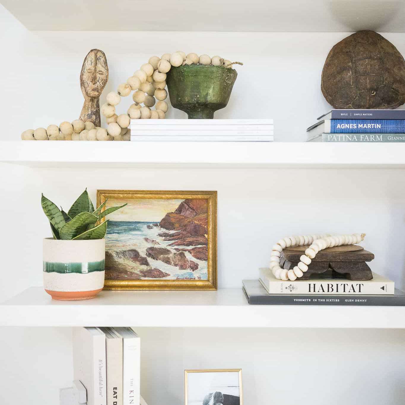 架子装饰着沙滩书，绘画，陶瓷和其他传家宝