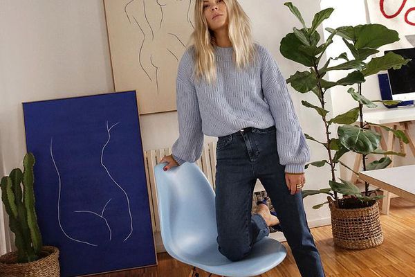 跪在椅子的妇女在有植物和艺术的客厅