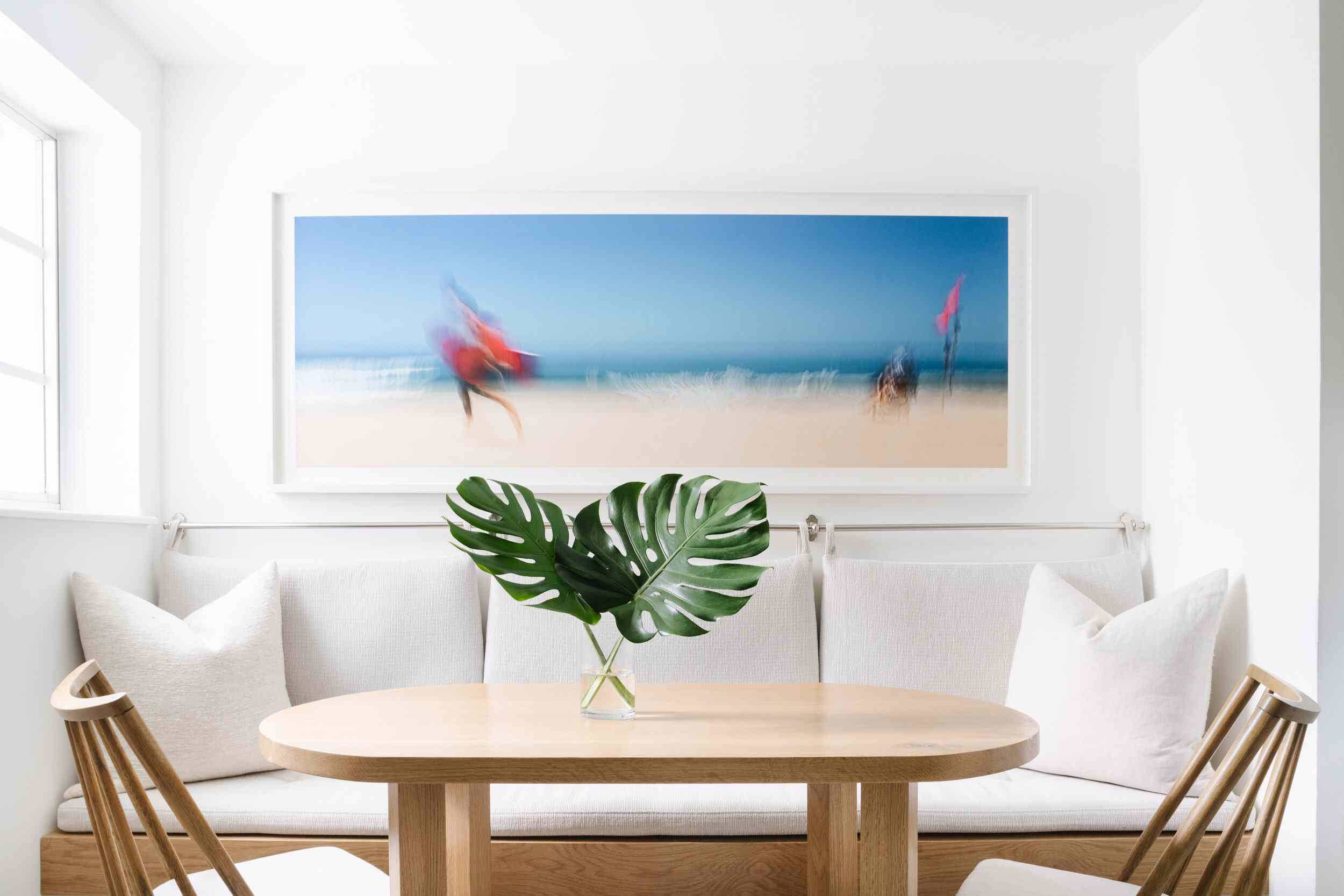 一张小木桌，上面放着一个玻璃花瓶，里面装满了两片怪兽的叶子