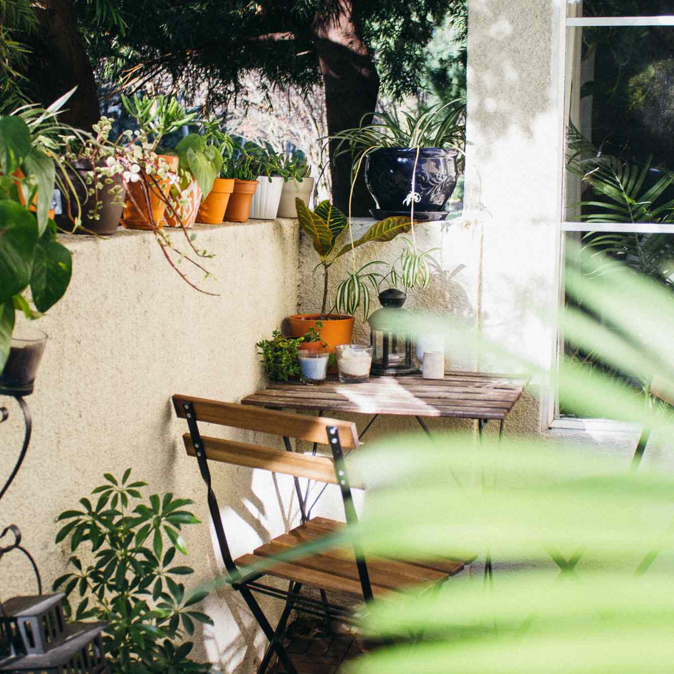 一个小阳台上装饰着一张小酒馆的桌子，两把椅子和成吨的植物