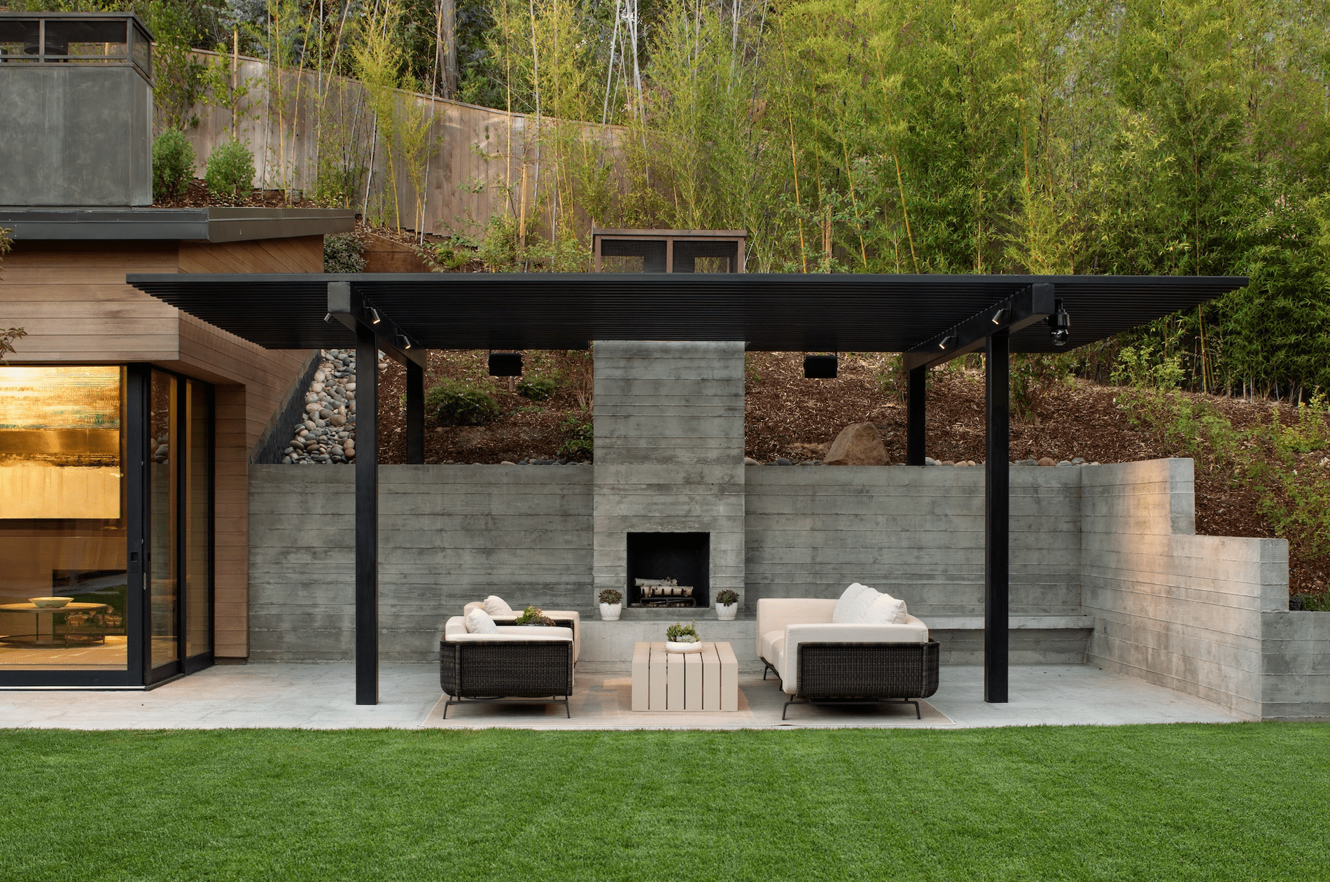 一座现代风格的户外壁炉，配以光滑的黑色藤架