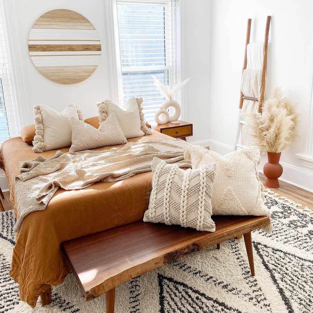 波西米亚风格的卧室，带有中性纹理的枕头和毯子。