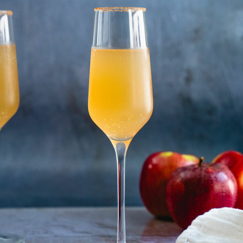 在香槟长笛的苹果汁mimosa与肉桂糖轮辋。