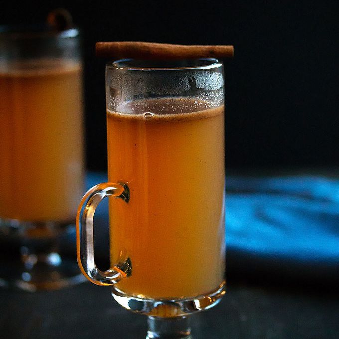 在玻璃杯子的热黄油兰姆酒冠上肉桂棒。