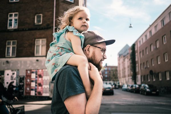 一个男人背着他的小女儿在城市里走着。