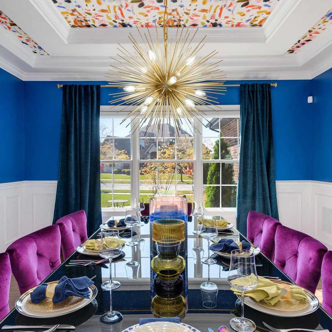 大胆的用餐室配有钴墙和明亮的紫色天鹅绒椅子