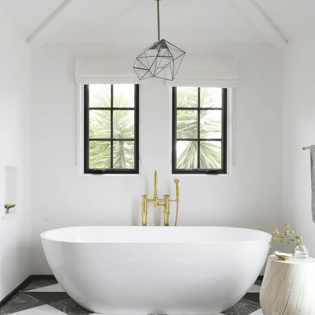 一间装饰艺术风格的浴室，铺着大胆的瓷砖地板，一个独立式浴缸，还有一盏几何吊灯